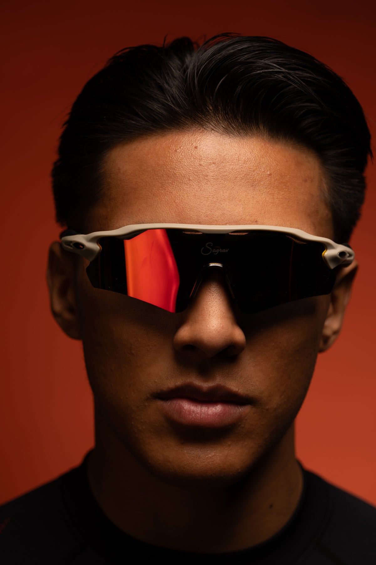 Emiliano wearing vanguard sunglasses against original red background