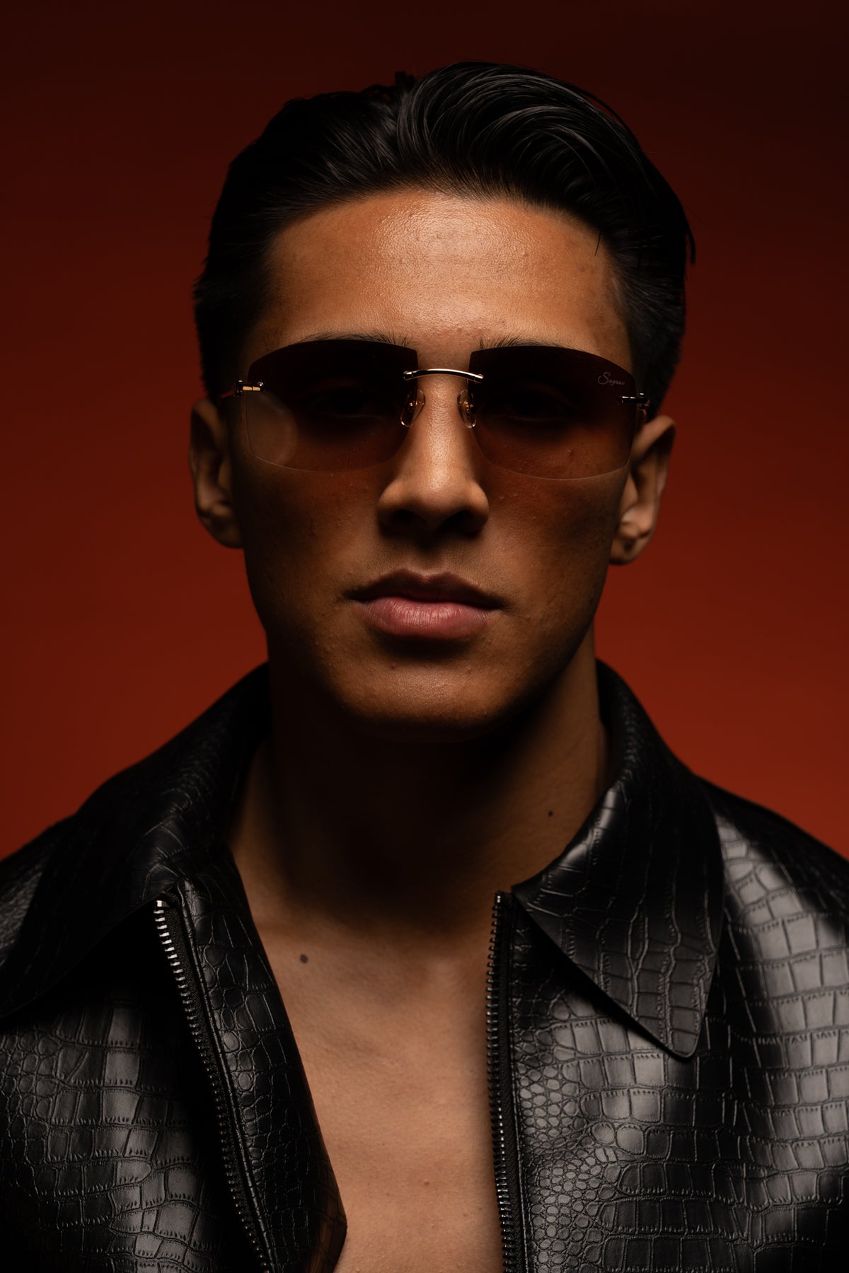 Emiliano wearing consigliere sunglasses against original red background